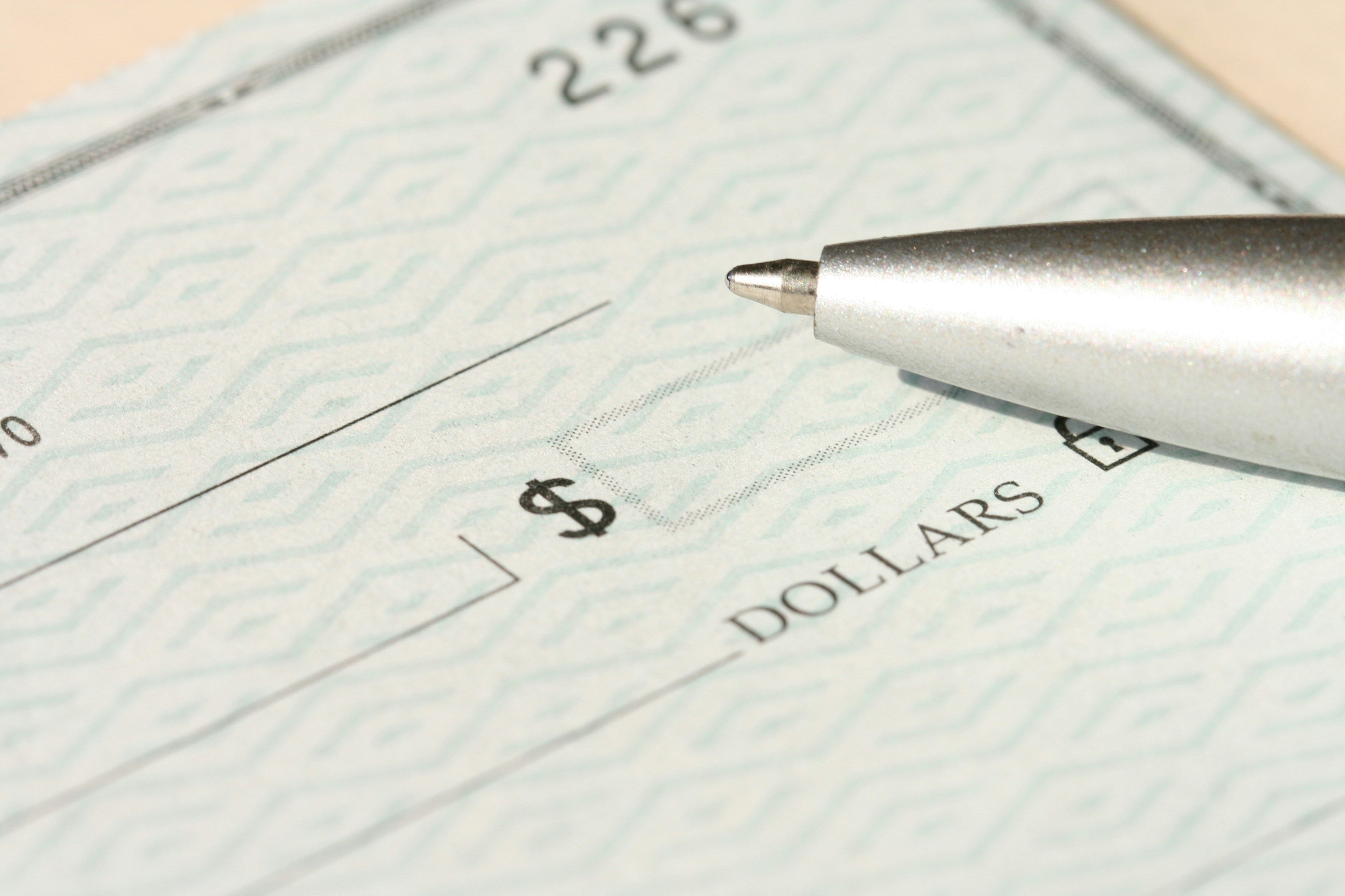 A pen resting on a US check, illustrating a returned bank deposit
