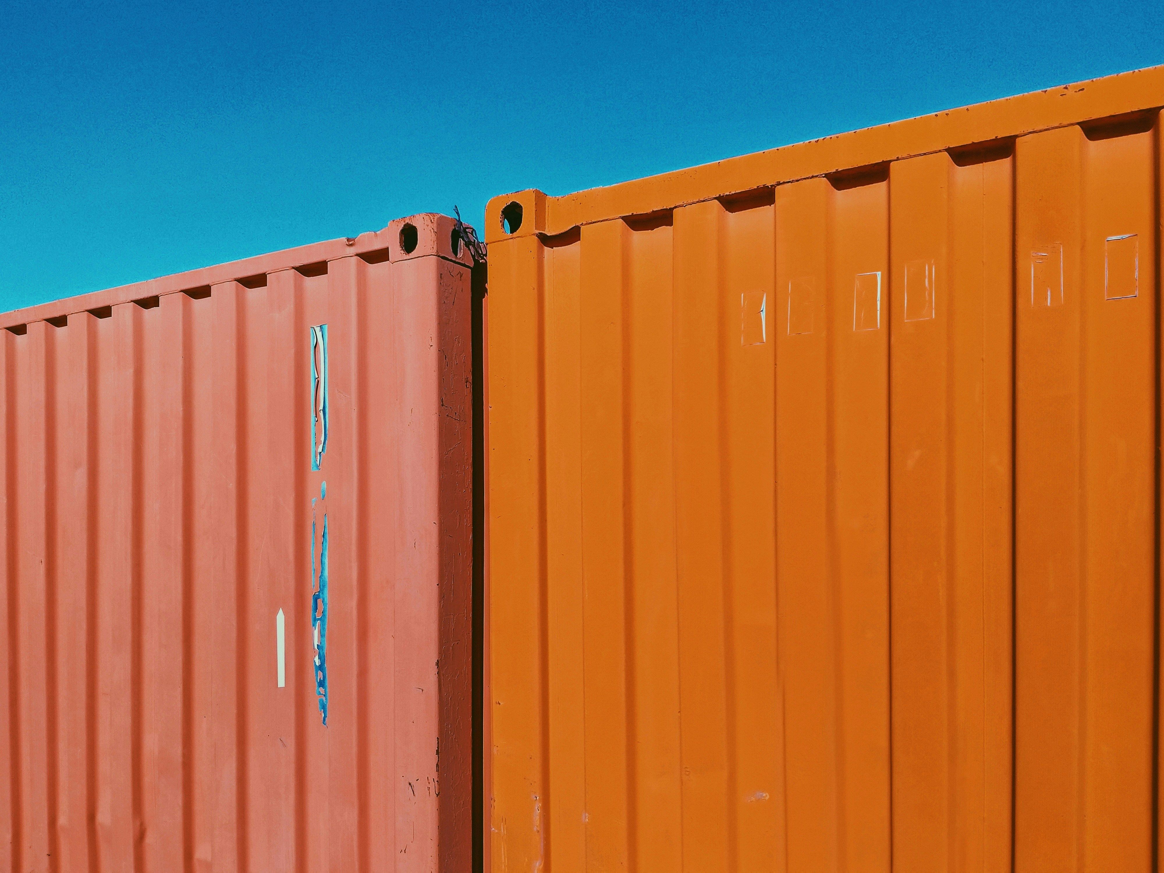 Orange shipping containers under a blue sky representing the delayed CAPE Phase 3 launch