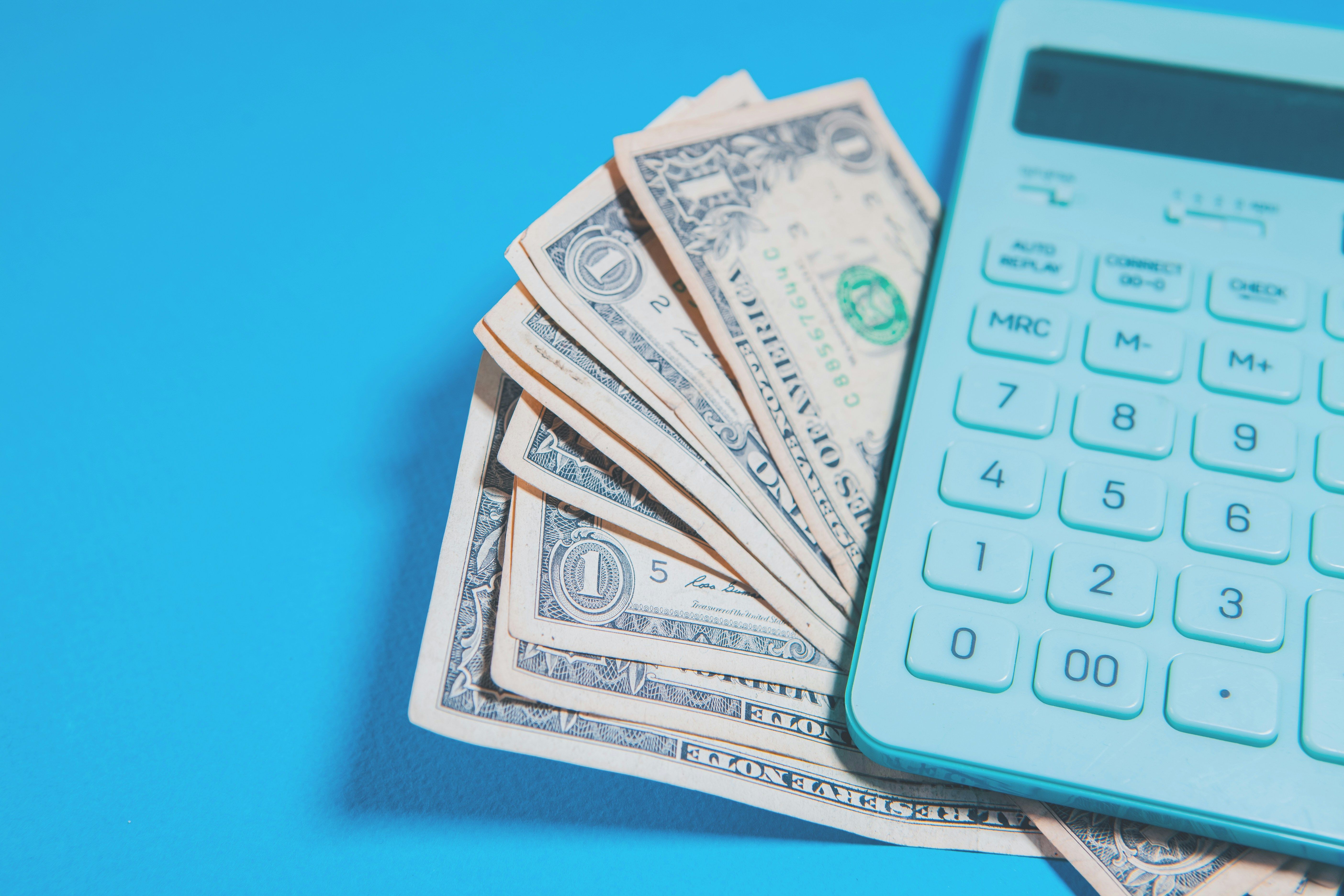 U.S. dollar bills and a calculator on a blue background, illustrating IEEPA refund interest math